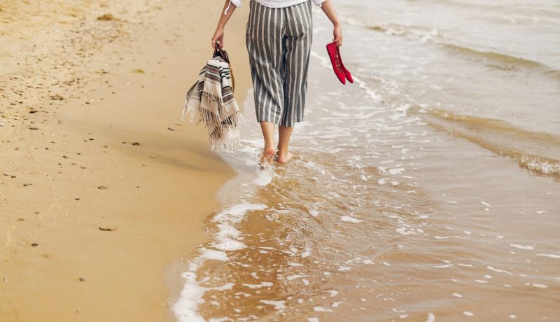 Woman walking barefoot on beach